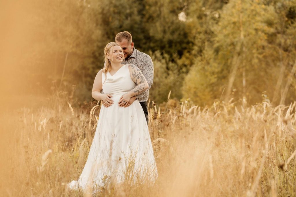 After Wedding Shooting Braut mit Brautkleid auf einer grünen Wiese im Sonnenuntergang