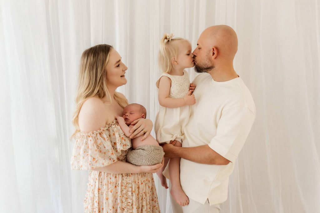 Baby gehalten von Mama und Papa beim Babyshooting mit Geschwisterchen