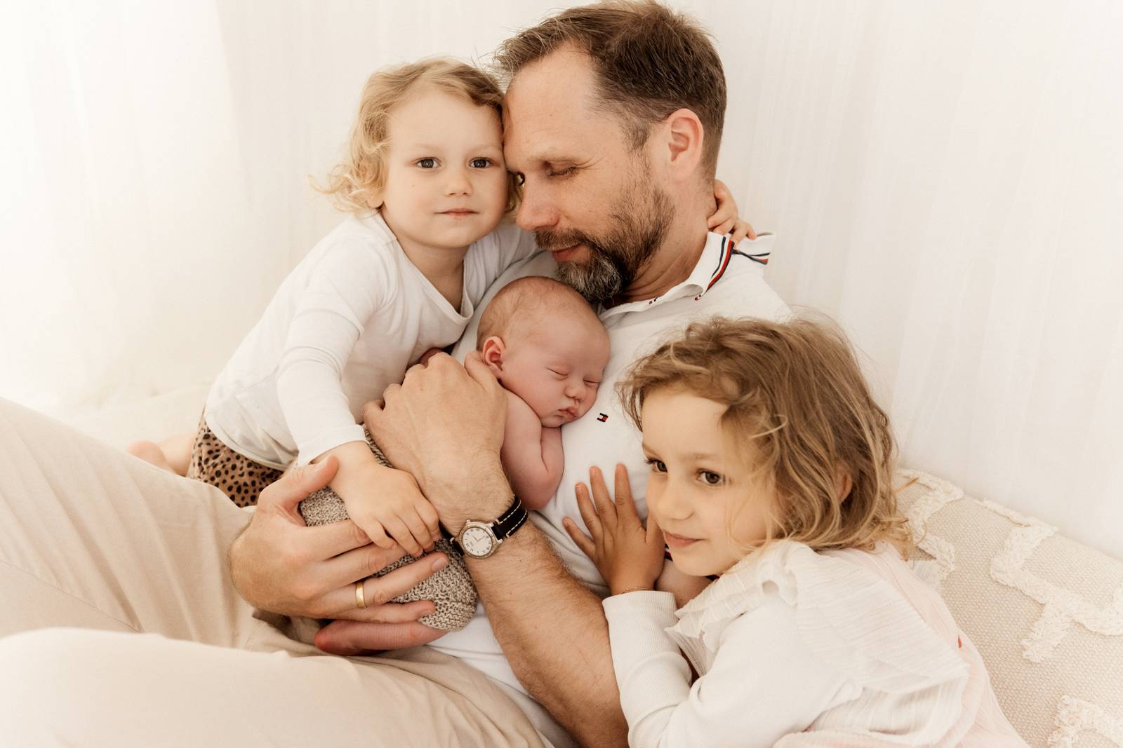 Baby gehalten von Papa und Geschwistern beim Babyshooting