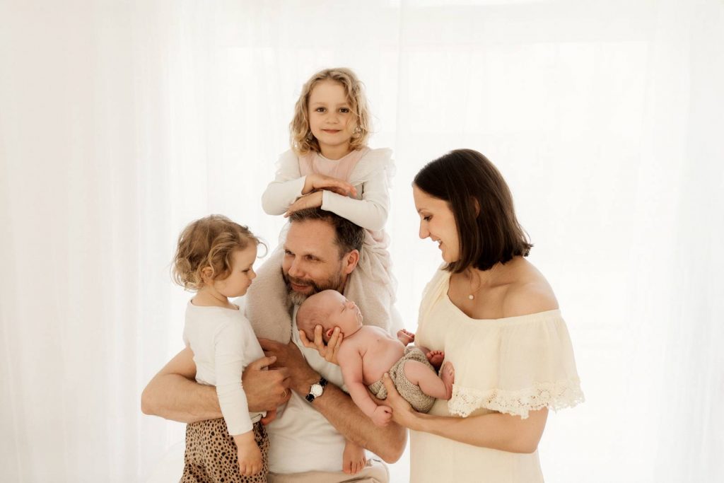Baby gehalten von Mama und Papa beim Babyshooting mit Geschwisterkind