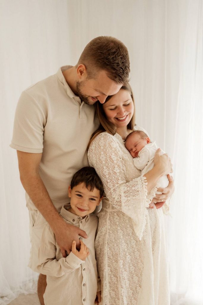 Baby gehalten von Mama und Papa beim Babyshooting mit Geschwisterkind