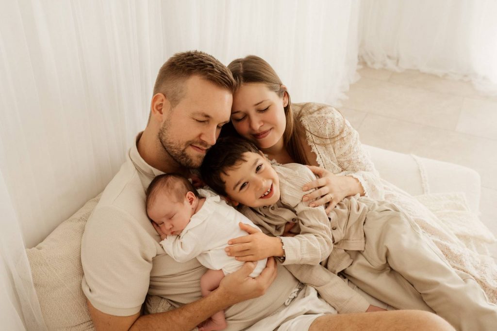 Baby gehalten von Mama und Papa und Geschwisterkind beim Babyshooting