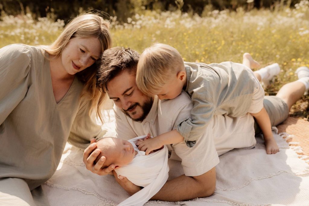 Baby gehalten von Mama und Papa beim Babyshooting draußen Outdoor