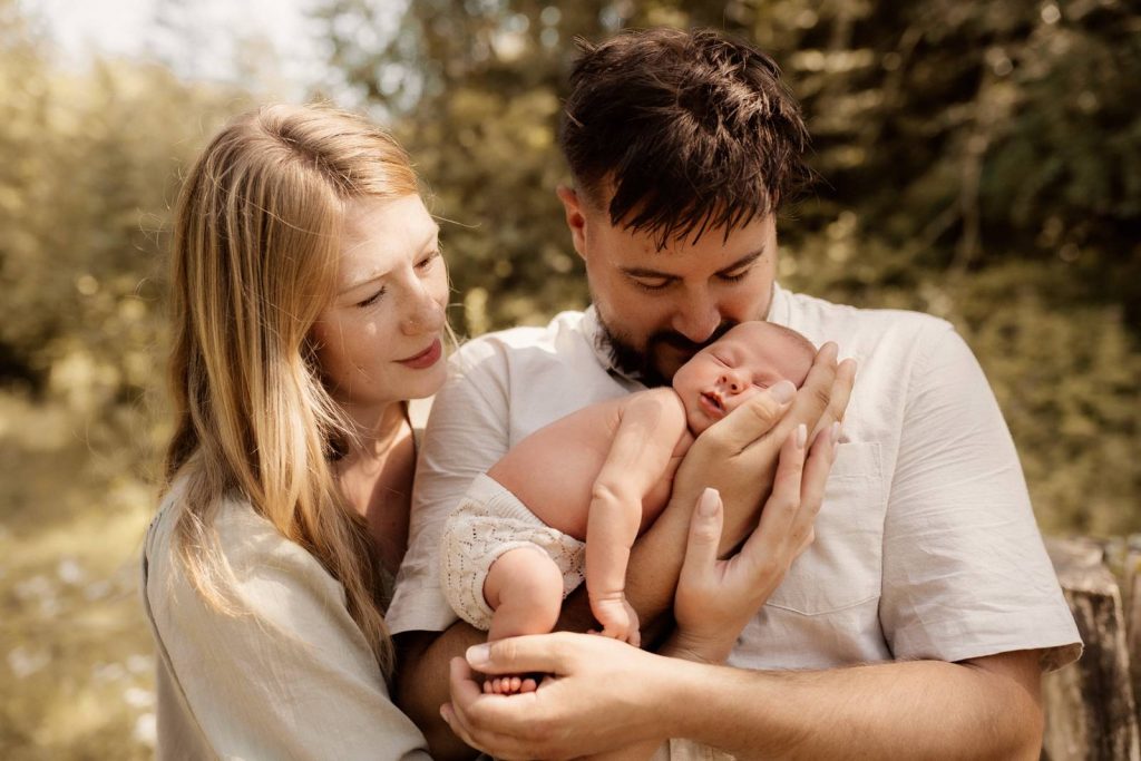 Baby gehalten von Mama und Papa beim Babyshooting draußen